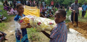 Two children waiting to place their floral tributes on the top of the grave